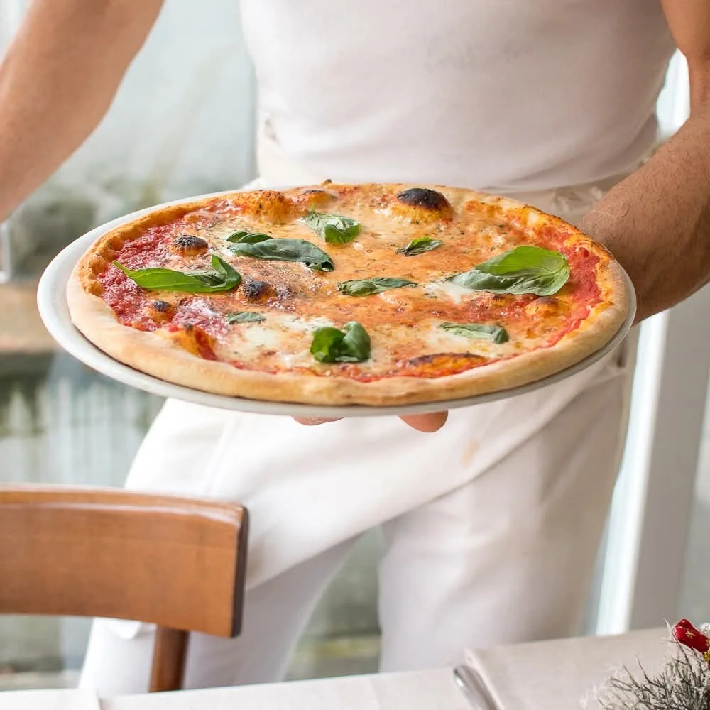 Pizza appena sfornata nelle mani del pizzaiolo