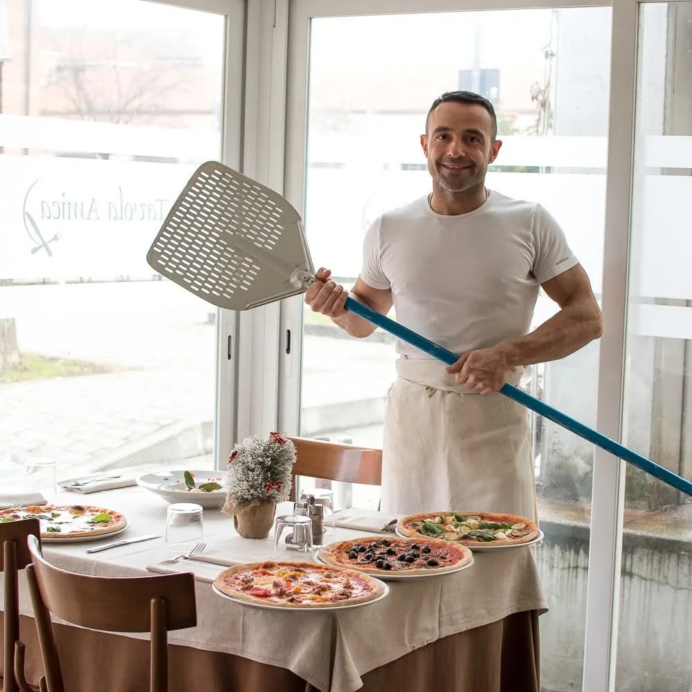 Il pizzaiolo di Tavola Amica al lavoro con la pala